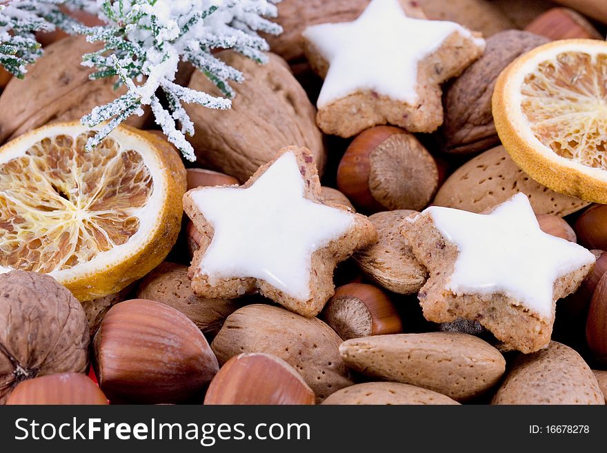 Closeup of star-shaped cinnamon biscuits with hazelnuts, almonds and dried oranges