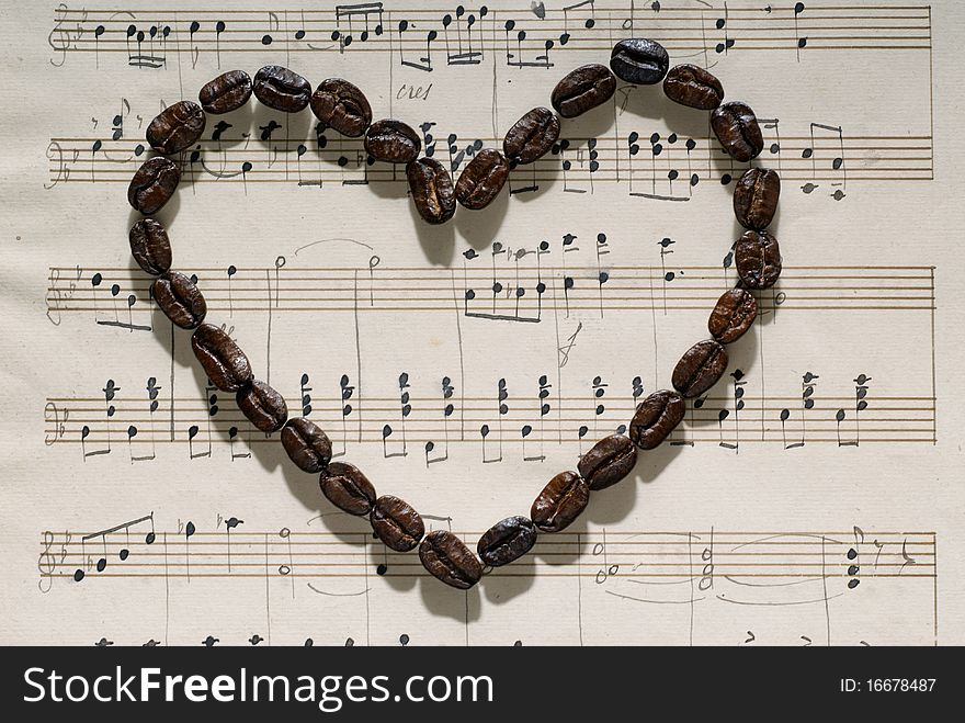 Coffee beans in the shape of heart on a musical score. Coffee beans in the shape of heart on a musical score