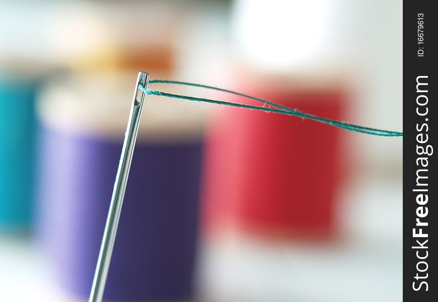 Close up of sewing needle with green thread.