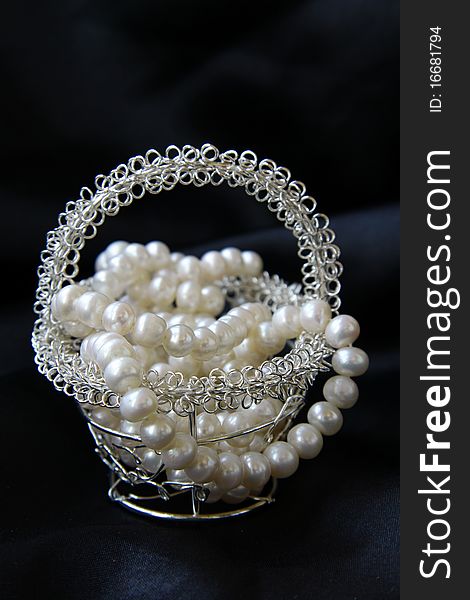 Jewelry pearls in a silver basket on a black background. Jewelry pearls in a silver basket on a black background