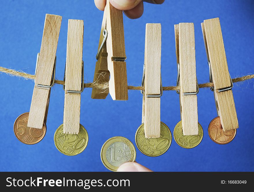 Hands clipping euro coins with clothespeg. Hands clipping euro coins with clothespeg