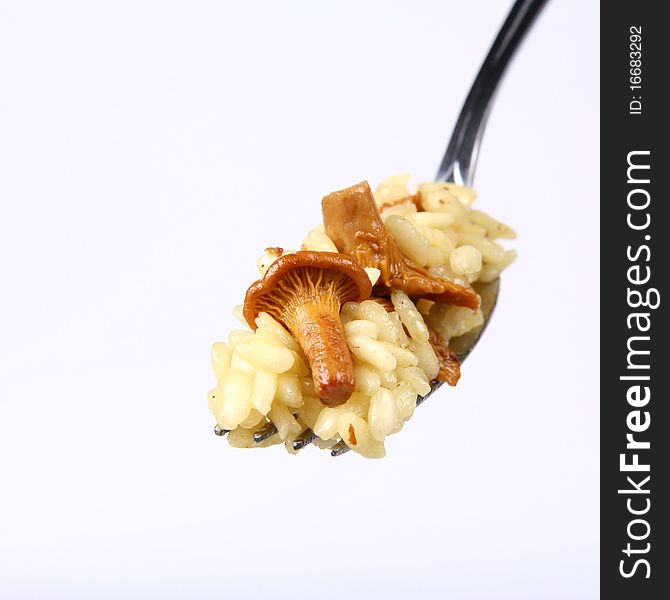 Risotto with mushrooms on a fork on white background