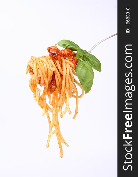 Spaghetti with sauce bolognese hanging on a fork decorated with fresh basil. Spaghetti with sauce bolognese hanging on a fork decorated with fresh basil