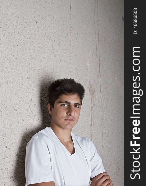 Young teenage boy leaning against a wall in anurban setting. Young teenage boy leaning against a wall in anurban setting.