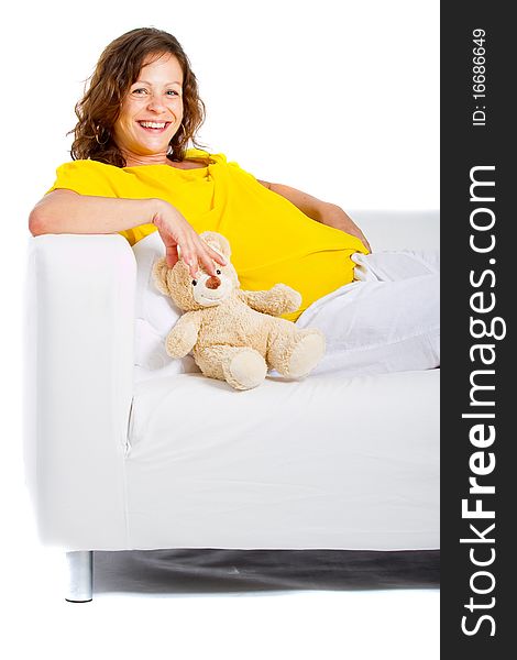 Young expecting mother is sitting on a couch at home. Highkey image over pure white background.