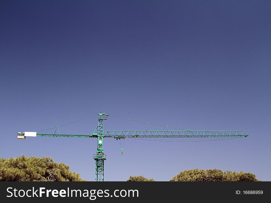 Lifting crane & trees on sky background. abstract industrial image