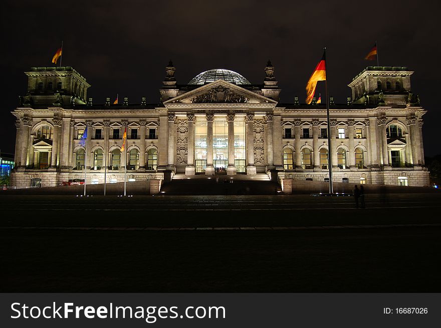 The Reichstag at night illuminated with developing the wind flags