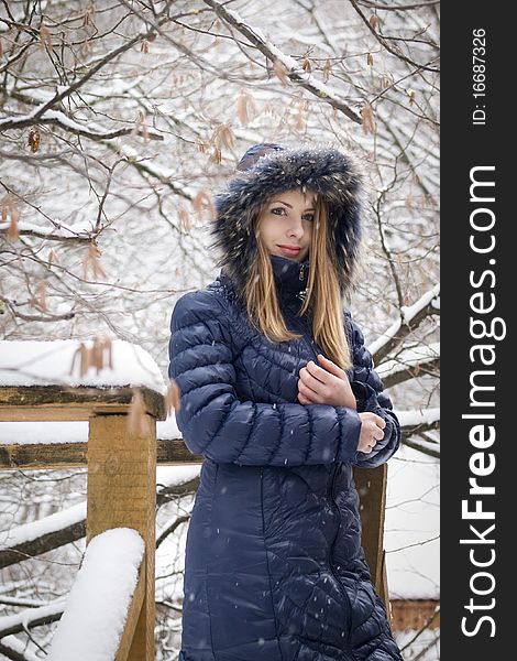 Young woman in blue coat outdoors in snow garden. Young woman in blue coat outdoors in snow garden