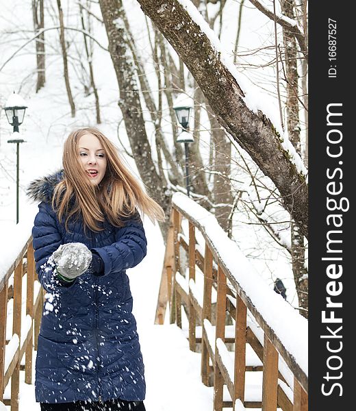 Young woman in blue coat outdoors playing with snow in snow forest. Young woman in blue coat outdoors playing with snow in snow forest