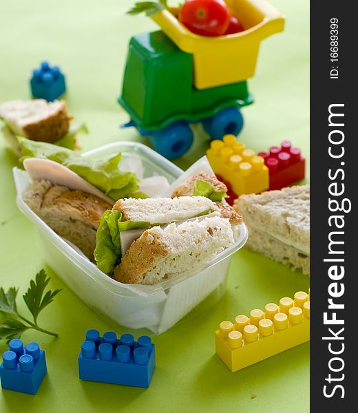 Breakfast with ham and lettuce for child with toys on background. Breakfast with ham and lettuce for child with toys on background