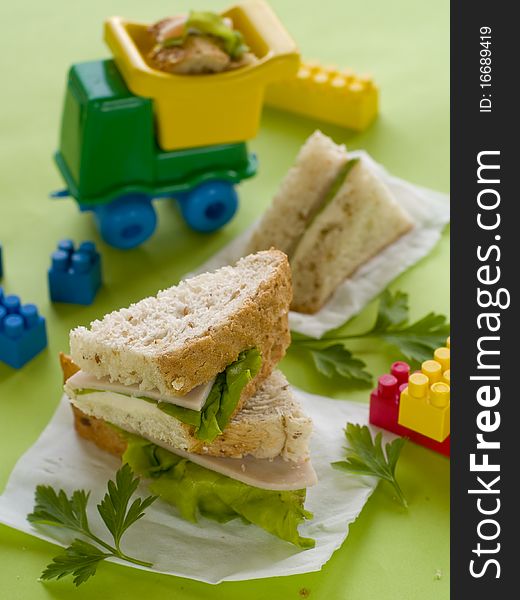 Breakfast with ham and lettuce for child with toys on background. Breakfast with ham and lettuce for child with toys on background