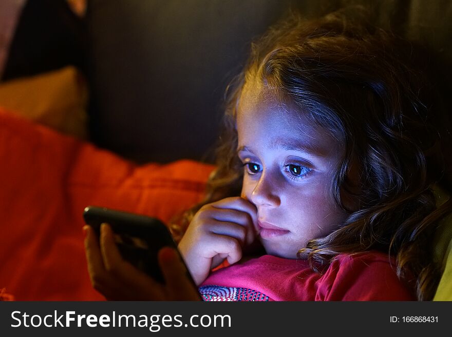 4 year old girl looks with interest at her cell phone
