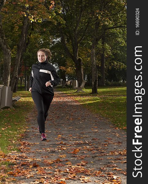 Beautiful female athlete running in park on a beautiful autumn day. Beautiful female athlete running in park on a beautiful autumn day.