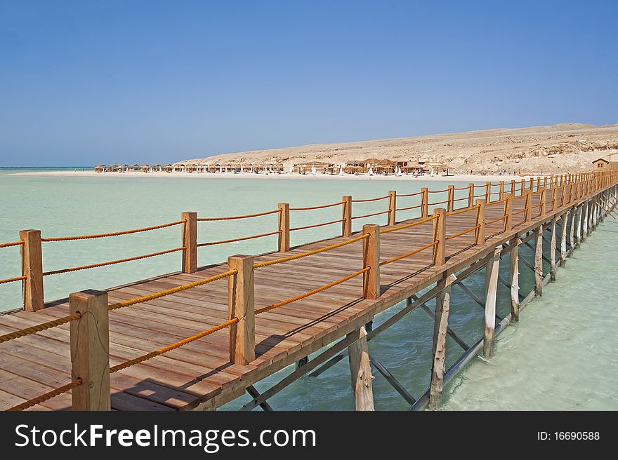 View of a tropical beach on an island with a small wooden jetty. View of a tropical beach on an island with a small wooden jetty