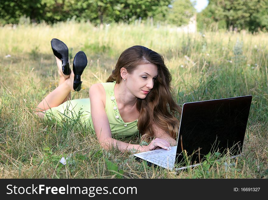 Beautiful woman lying on grass with laptop. Beautiful woman lying on grass with laptop