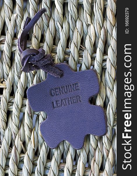 A close up of a genuine leather tag on a wicker surface