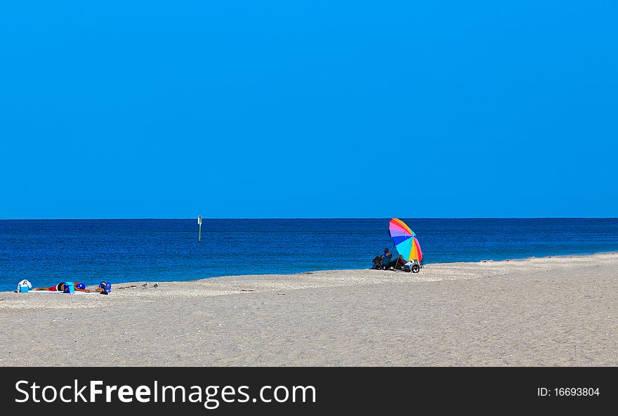Colorful Beach Umbrella on a sandy beach, blue sky and blue ocean