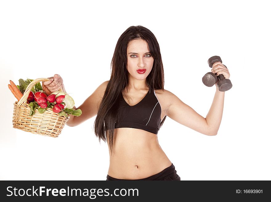 A woman is holding up a basket of vegetables and some weights. A woman is holding up a basket of vegetables and some weights.