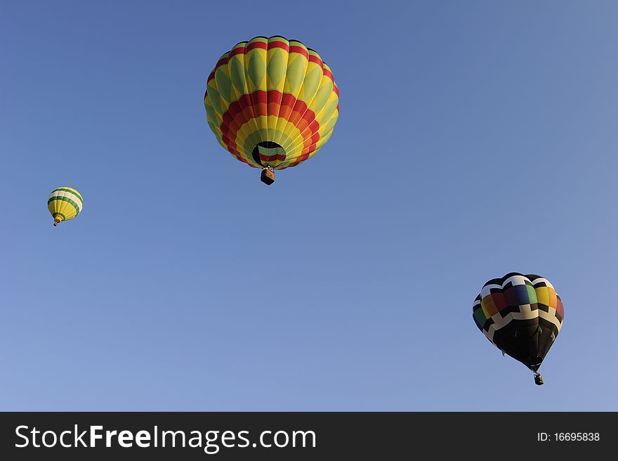 Three multi colored hot air balloons against a clear blue sky. Three multi colored hot air balloons against a clear blue sky