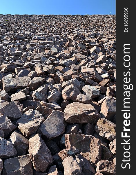 Construction area full of stone in brownness, under blue sky, shown as perspective and industrial solid and powerful. Construction area full of stone in brownness, under blue sky, shown as perspective and industrial solid and powerful.