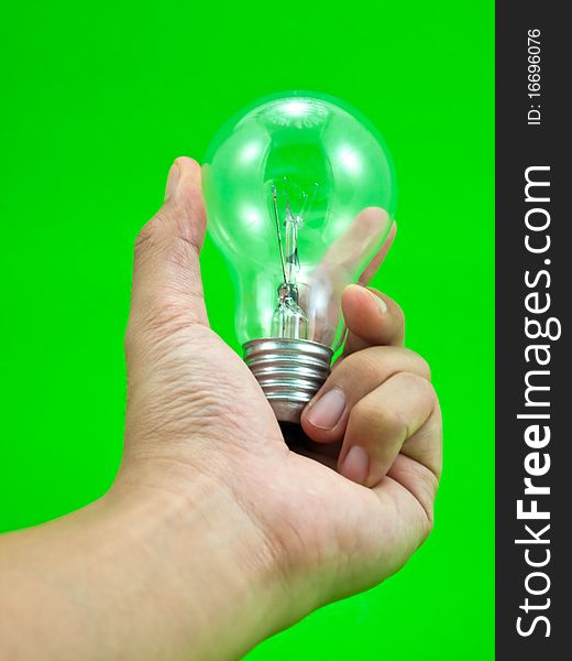 Lightbulb in a hand isolated on green background. Lightbulb in a hand isolated on green background.