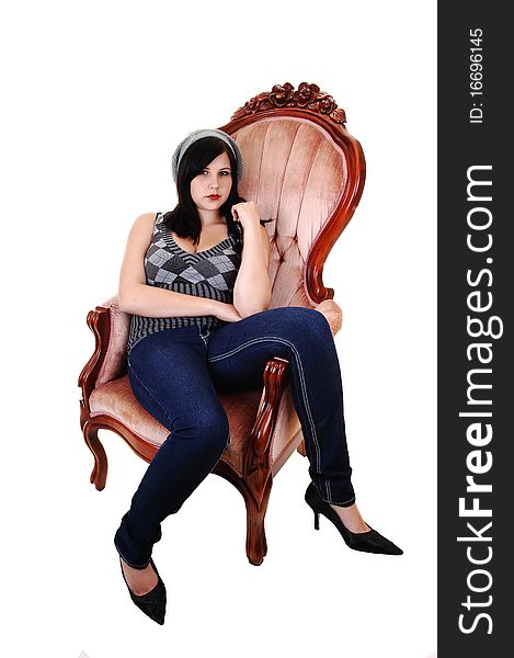 A young pretty woman in jeans, high heels and a had, sitting in an old pink armchair, relaxing, on white background. A young pretty woman in jeans, high heels and a had, sitting in an old pink armchair, relaxing, on white background.
