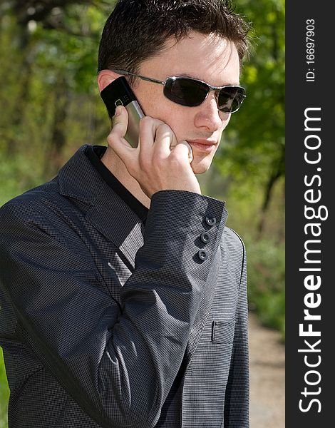 Man in sunglasses and jacket talks on cell phone