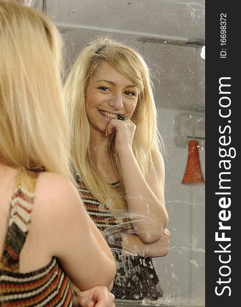 Blonde girl admiring her beauty in old mirror. Blonde girl admiring her beauty in old mirror