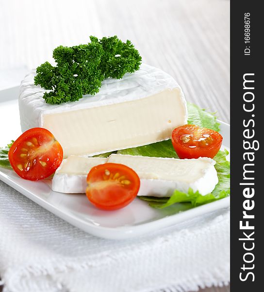 Soft cheese sliced on plate with tomato