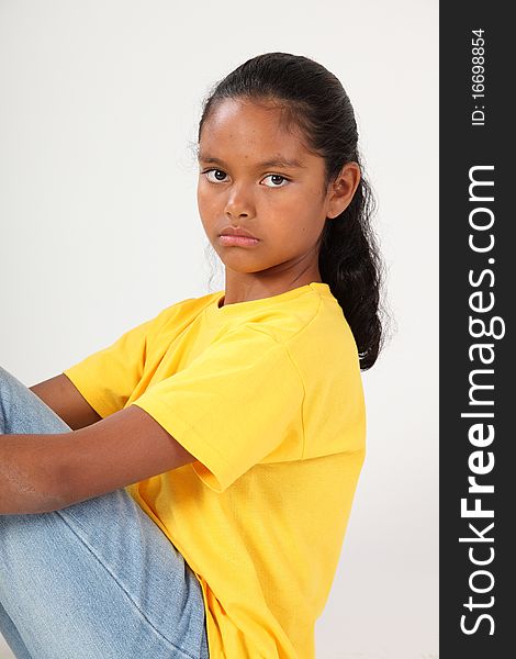 Close up portrait of serious young ethnic school girl, 9, staring straight at camera. Studio shot against white background. Close up portrait of serious young ethnic school girl, 9, staring straight at camera. Studio shot against white background