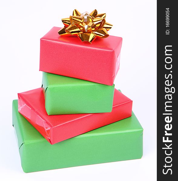 Gifts in green and red wrapping with a golden bow on white background