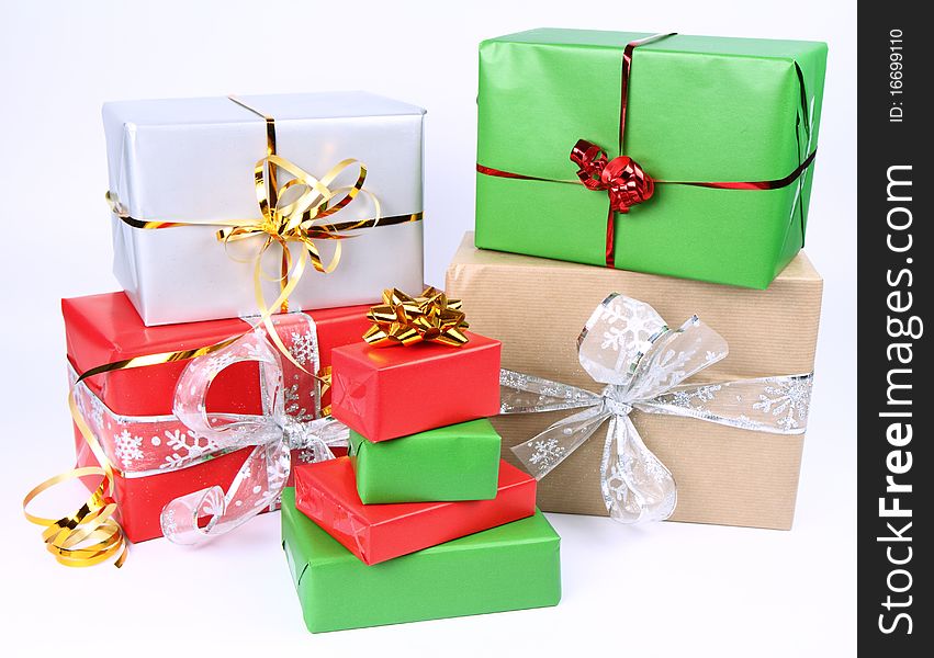 Gifts in silver, green, brown and red wrapping with bows on white background