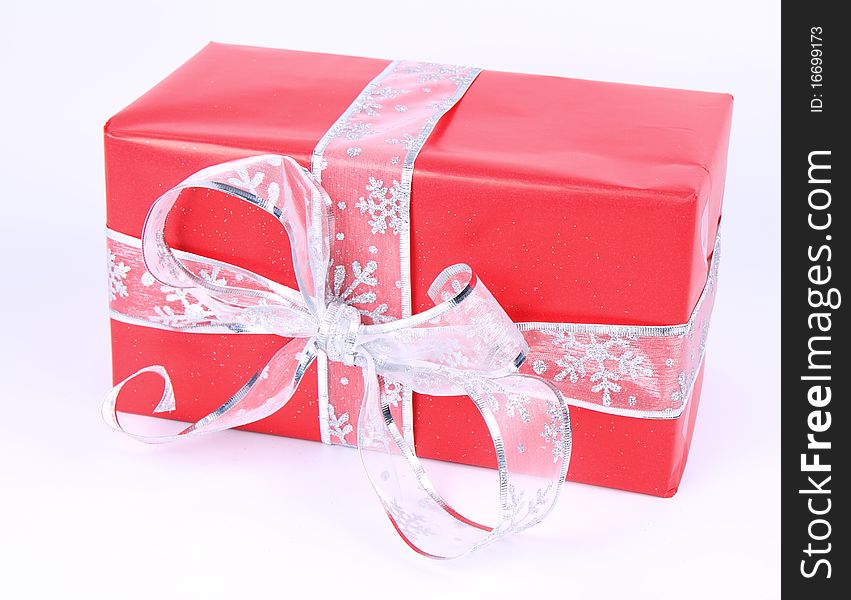 Gift in red wrapping with silver bow on white background