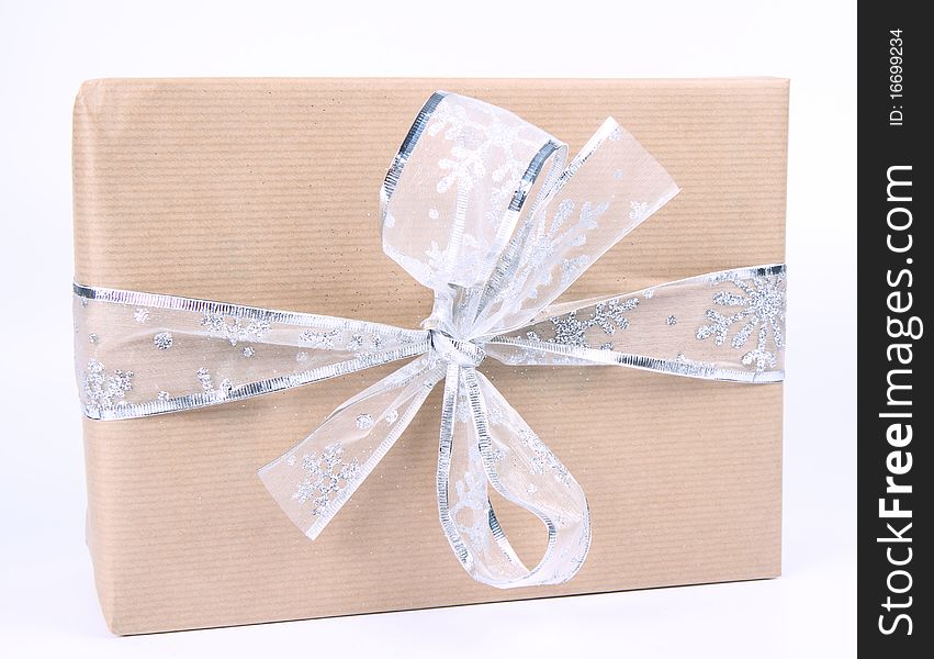Gift in paper wrapping with silver bow on white background