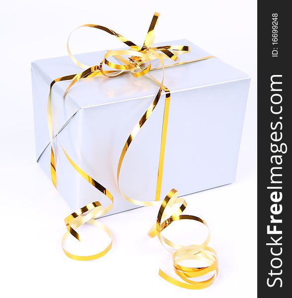 Gift in silver wrapping with gold bow on white background