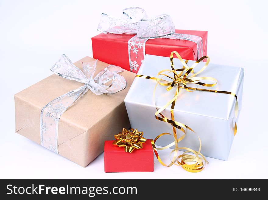 Gifts in silver, brown and red wrapping with bows on white background. Gifts in silver, brown and red wrapping with bows on white background