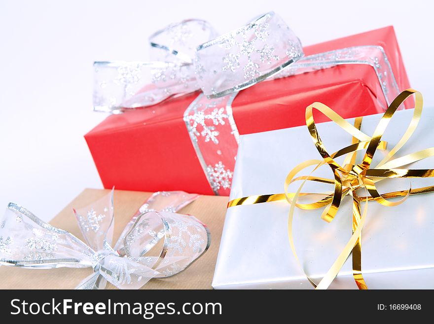 Gifts in silver, brown and red wrapping with bows on white background in close up
