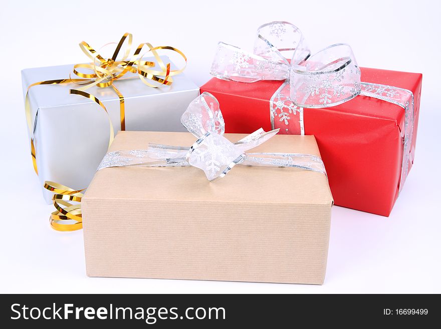 Gifts in silver, brown and red wrapping with bows on white background. Gifts in silver, brown and red wrapping with bows on white background