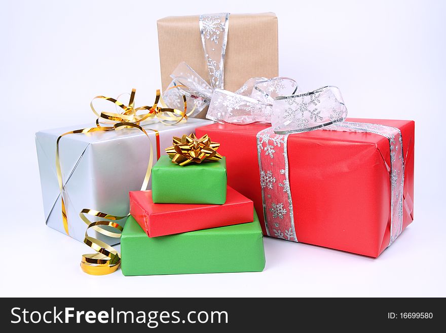 Gifts in silver, green, brown and red wrapping with bows on white background. Gifts in silver, green, brown and red wrapping with bows on white background
