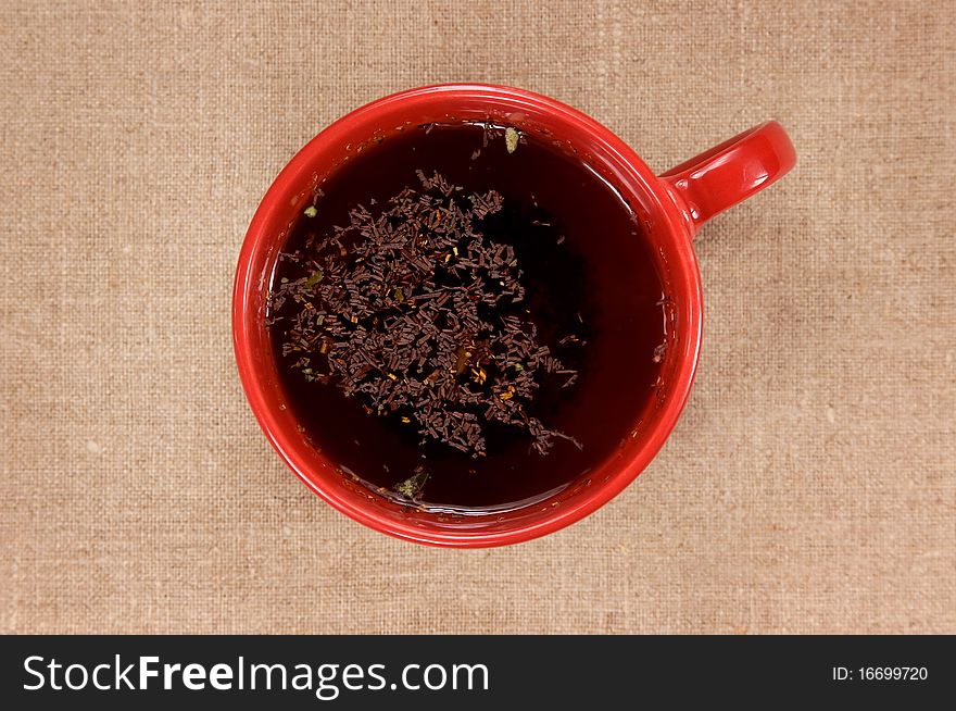 Red mug with black tea on fabric background. Red mug with black tea on fabric background