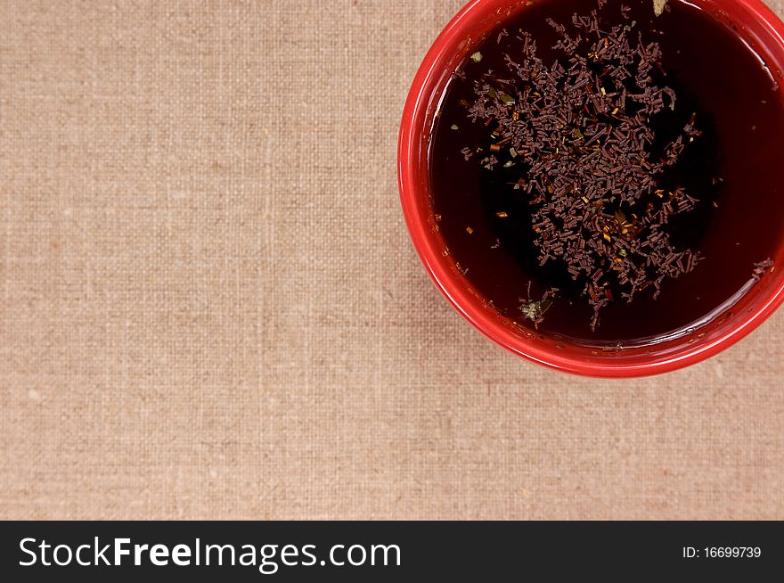 Red mug with black tea on fabric background. Red mug with black tea on fabric background