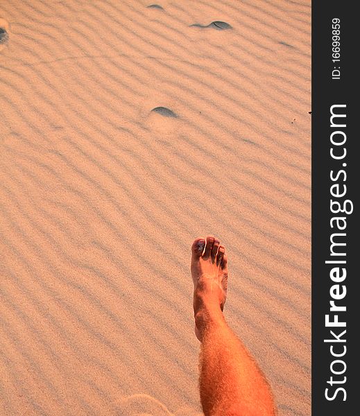 Foot making step on beach in sand ripples