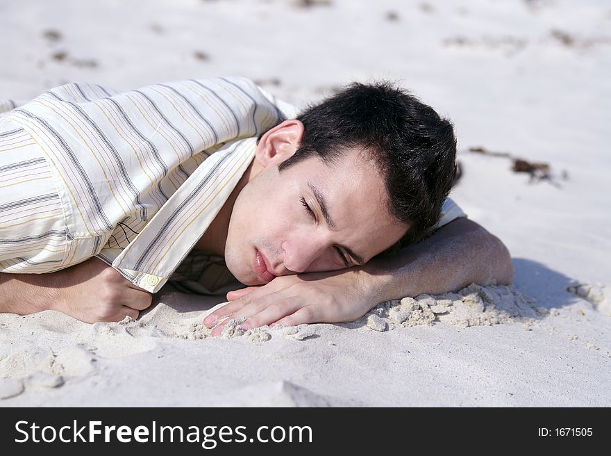 A young man sleeping at the beach