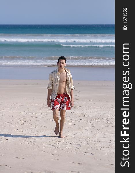 A handsome young man walking at a beach