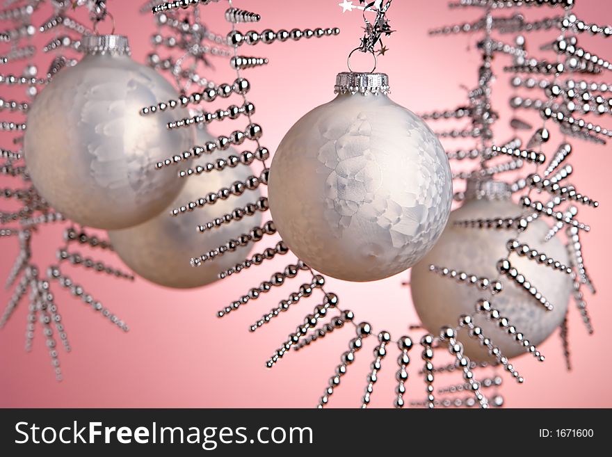 Christmas baubles hanging over pink background