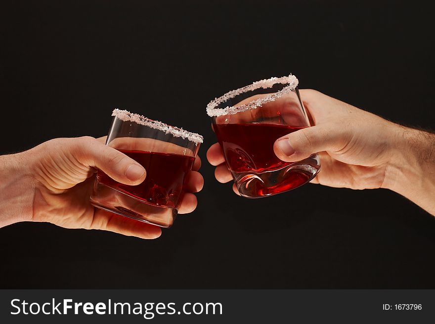 Two hands toasting with cherry brandy glasses on dark background. Two hands toasting with cherry brandy glasses on dark background