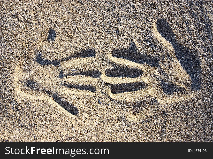 Two handprints in the sand in sunlight