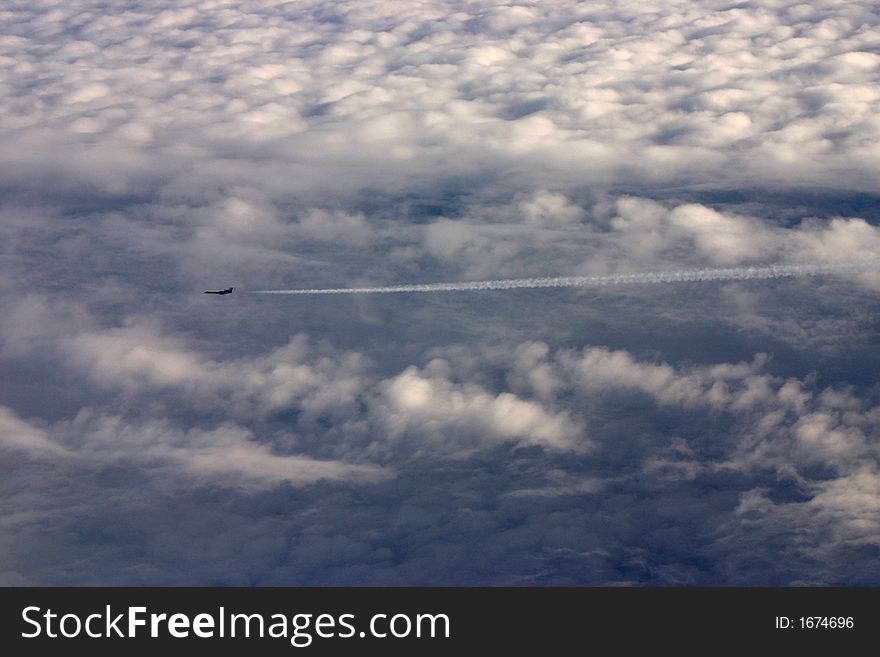 Airplane flying above fluffy clouds and leaving a condensation trail. Airplane flying above fluffy clouds and leaving a condensation trail