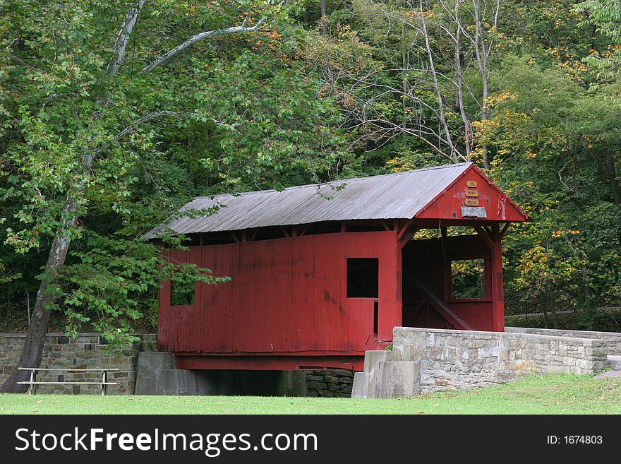 Classic Red Covered Bridge in a rural setting in early Autumn. Classic Red Covered Bridge in a rural setting in early Autumn.