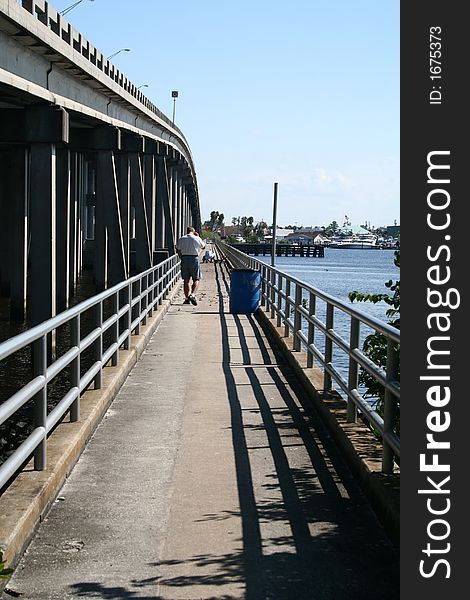 Man walking along fishing bridge. Man walking along fishing bridge.